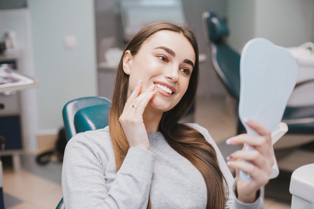 woman looking at beautiful teeth with porcelain veneers